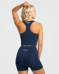 المنظر الخلفي لامرأة ترتدي قميصًا بدون أكمام أساسيًا باللون الأزرق الياقوتي من حمالة صدر رياضية وسروال قصير من WOMEN'S BEST مصنوع من قماش عالي الجودة.