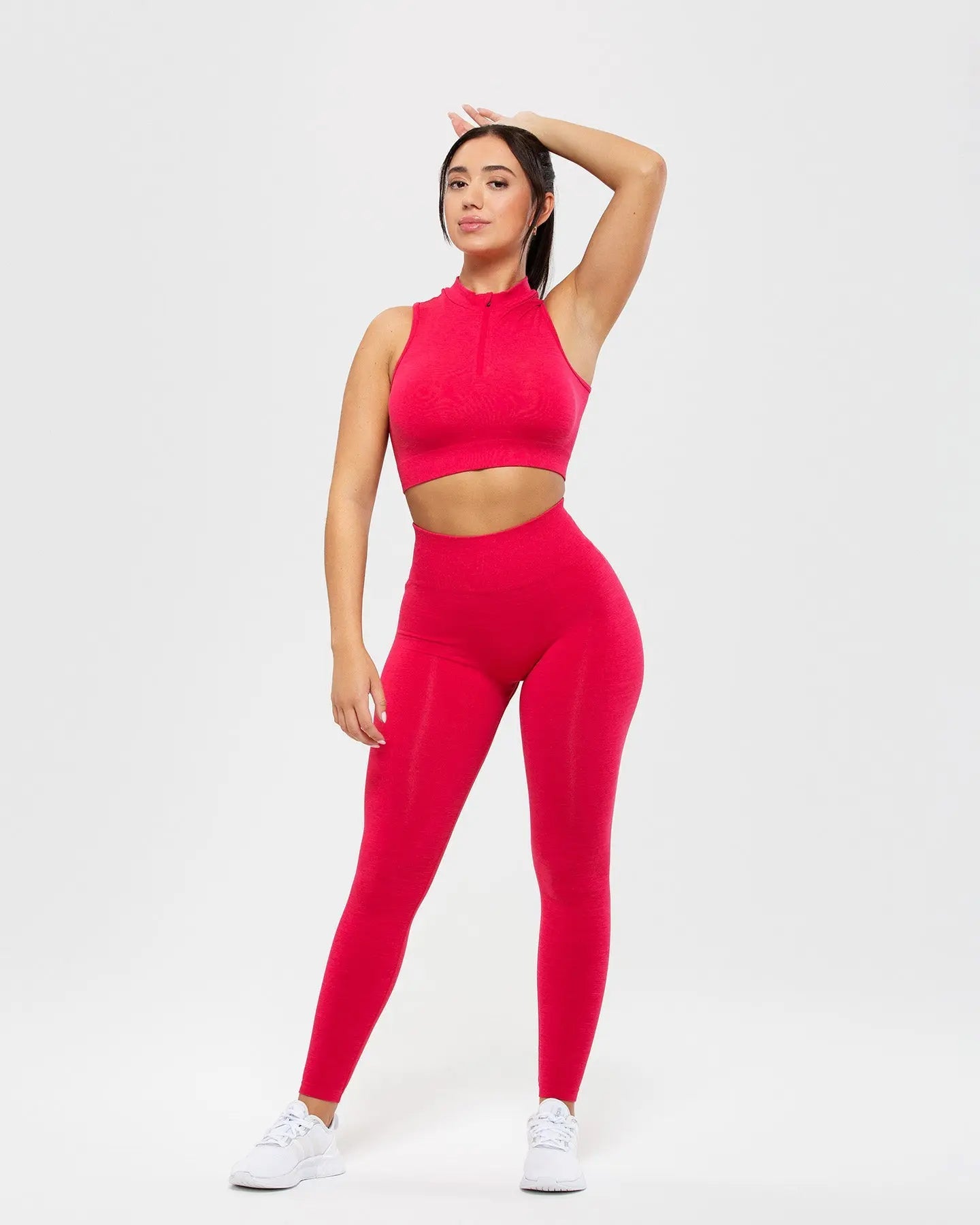 امرأة ترتدي قميص بدون أكمام Define Seamless Half Zip Crop باللون Viva Magenta من WOMEN'S BEST، مع سروال ضيق.