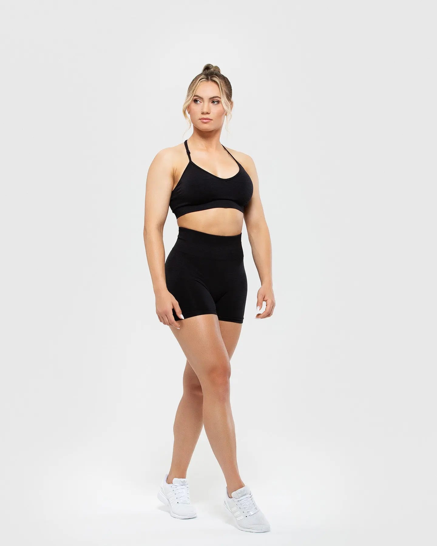 امرأة ترتدي شورتًا قصيرًا بدون خياطة من BEST Define Scrunch للسيدات باللون الأسود وحمالة صدر رياضية لتحقيق أقصى درجات الاسترخاء أثناء ممارسة التمارين.