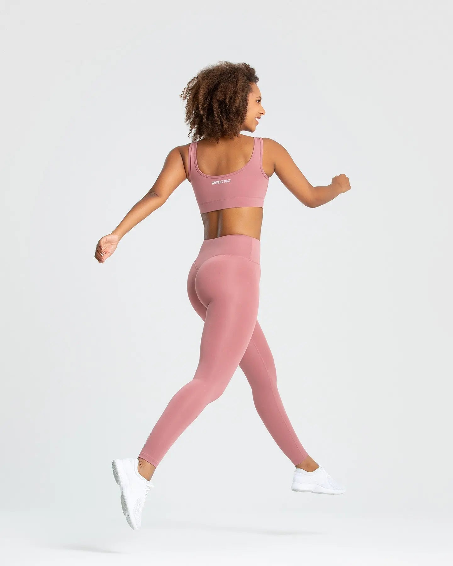 امرأة تمارس رياضة الجري مرتدية أفضل حمالة صدر رياضية أساسية للسيدات باللون الوردي الترابي.