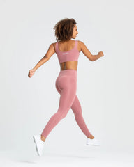 امرأة تمارس رياضة الجري مرتدية أفضل حمالة صدر رياضية أساسية للسيدات باللون الوردي الترابي.