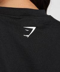 المنظر الخلفي لامرأة ترتدي تي شيرت أسود كبير الحجم من GS Fuel مع قميص Gymshark أبيض | شعار يونايتد نحن نتعرق.