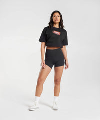 امرأة ترتدي Gymshark أسود | تي شيرت United We Sweat GS Fuel كبير الحجم.